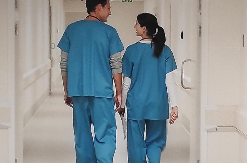 Twee verpleegkundigen wandelen door een gang, foto op de muur in het skillslab van verpleegkunde in Mechelen