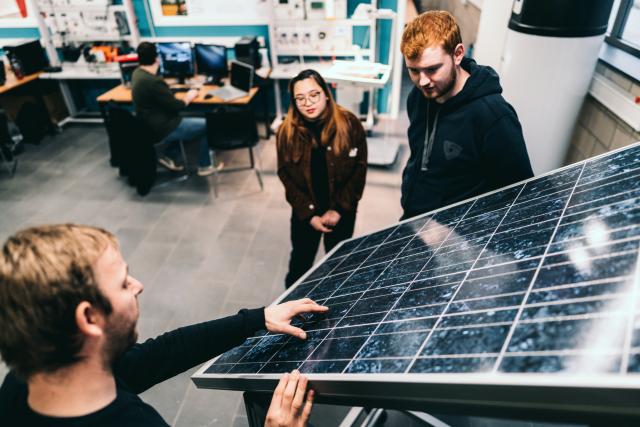 Studenten Energietechnologie en docent bespreken de werking van een zonnepaneel