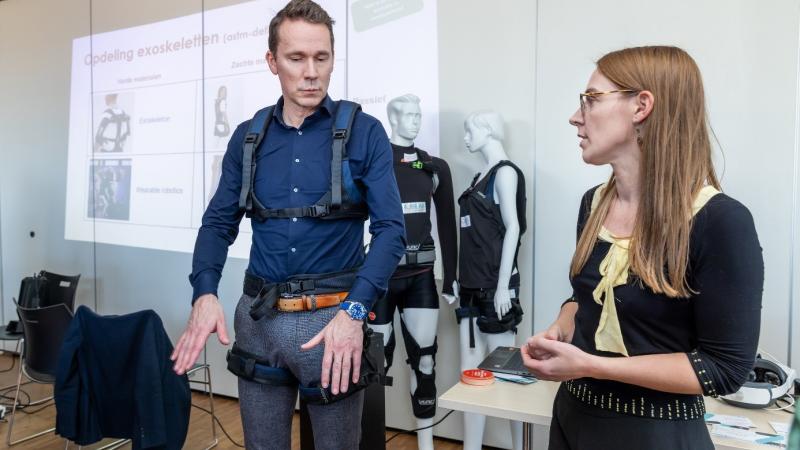 Foto van de minister met een exoskeleton 